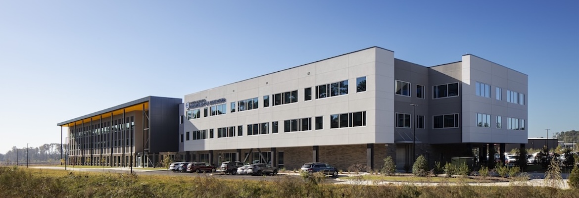 South-Carolina-Department-of-Education-Pyramid-Contracting-18 - Pyramid Contracting Modern office building with white and dark gray exterior, large windows, and a row of parked cars in front.